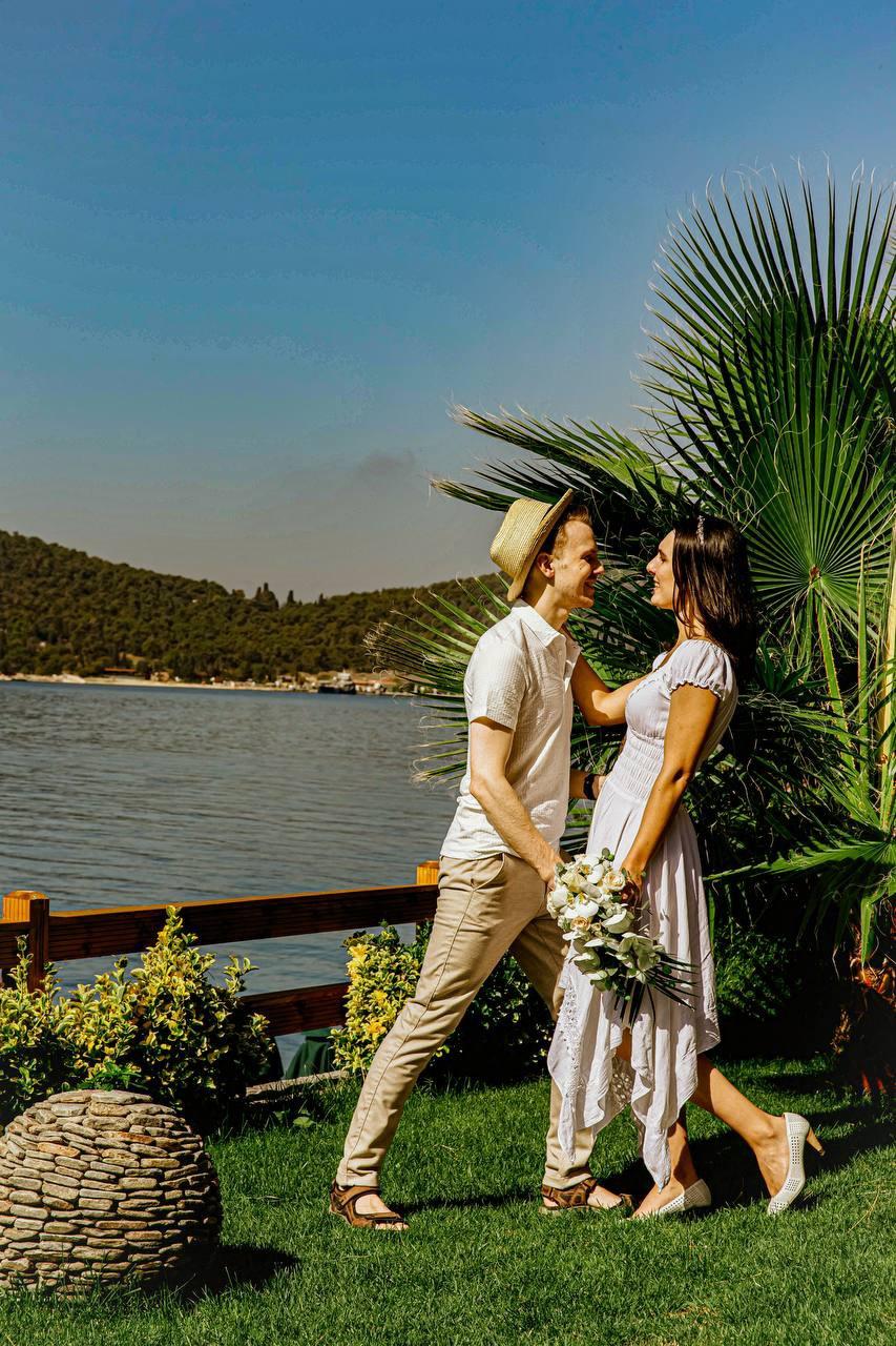 Deniz kıyısında palmiyelerin önünde poz veren gelin ve damat